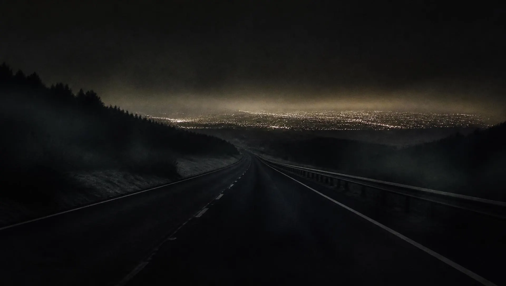 Night highway with a distant city glow